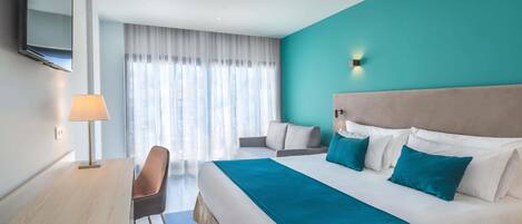 Ein Hotelzimmer mit einem großen Bett, einem Schreibtisch, einem Stuhl und einem Fernseher.