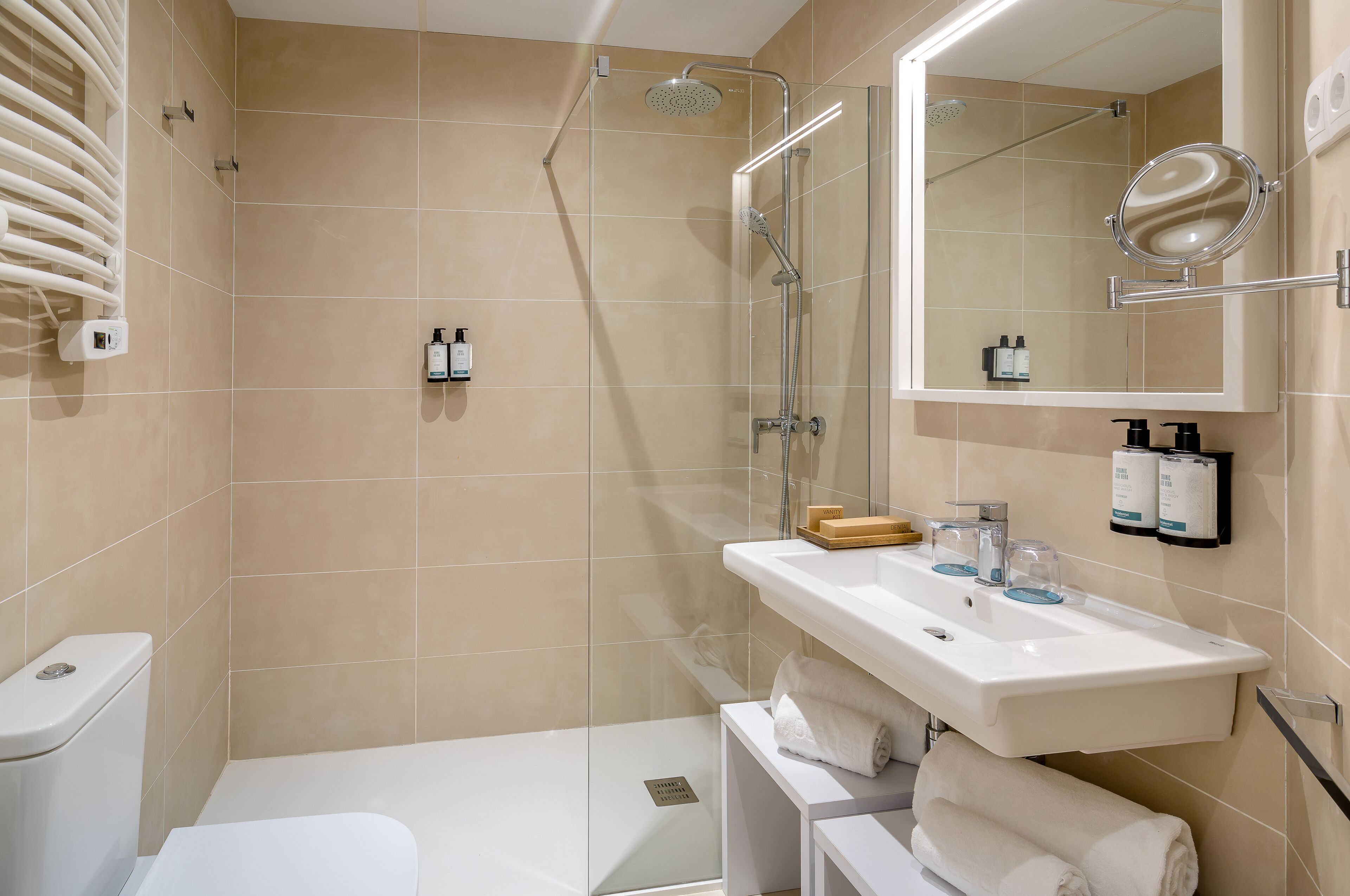 Une salle de bain moderne avec une douche à parois de verre, un lavabo blanc avec un miroir et des toilettes.