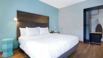 Una habitación de hotel moderna con una cama grande, una mesita de noche y un pequeño taburete.
