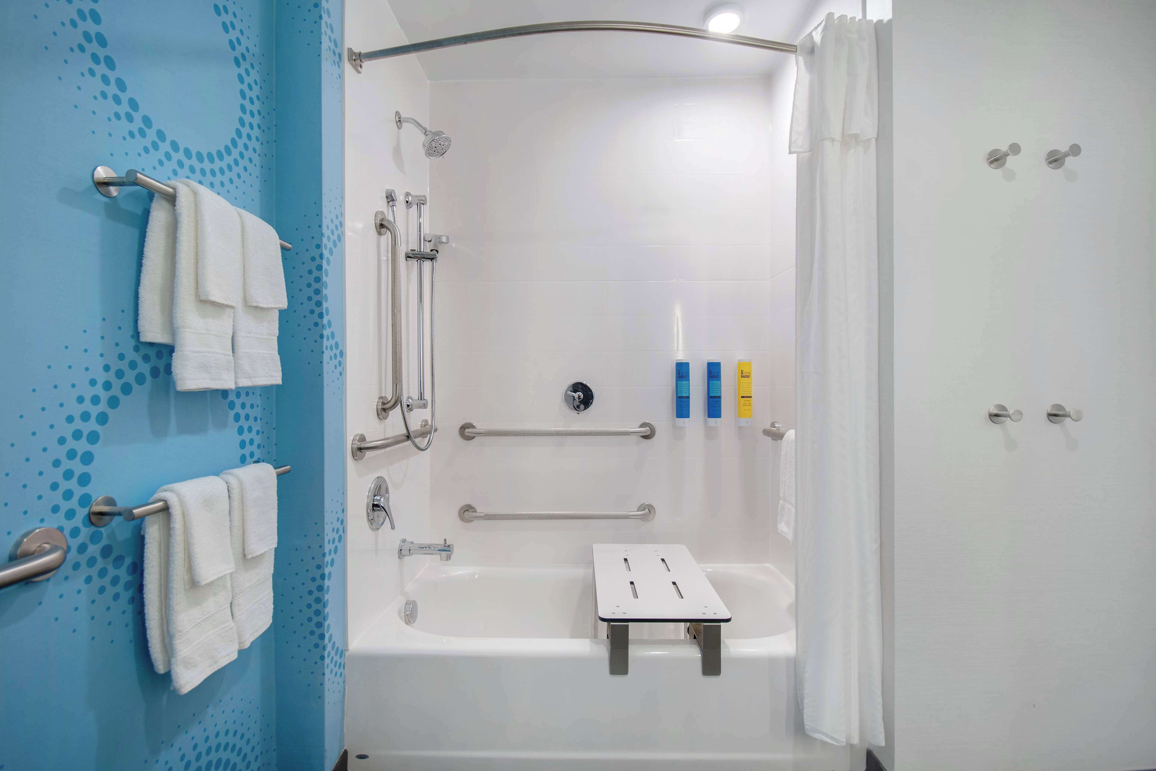A modern bathroom with a shower, grab bars, and a white bathtub.