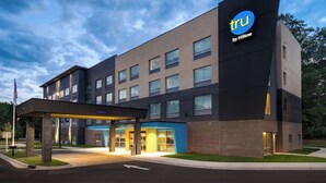 Ein modernes Hotel mit einem 'tru by Hilton'-Schild, einer überdachten Einfahrt und einer Ziegel-Fassade.