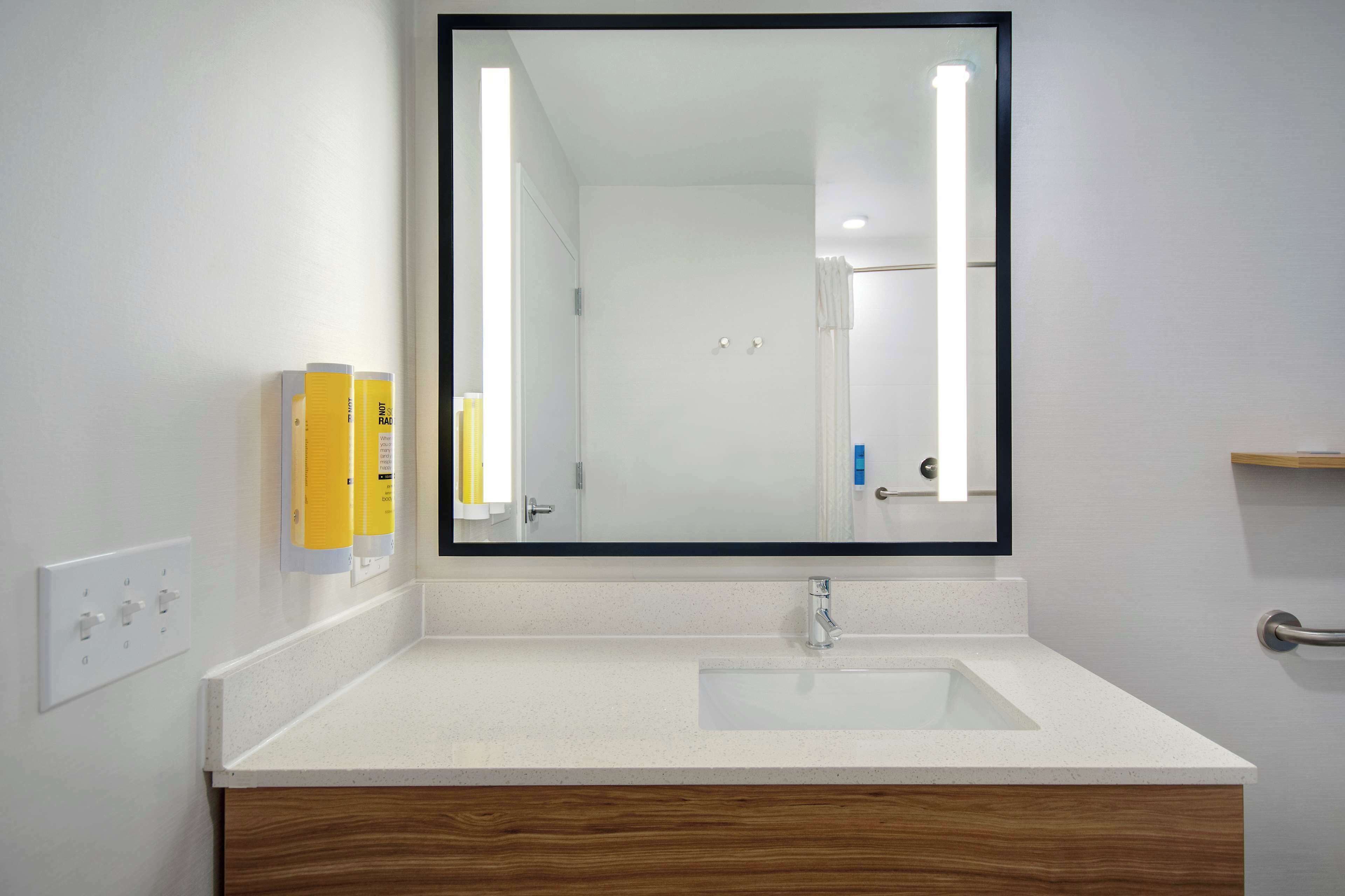 A bathroom with a white sink, a mirror, and a wooden vanity.