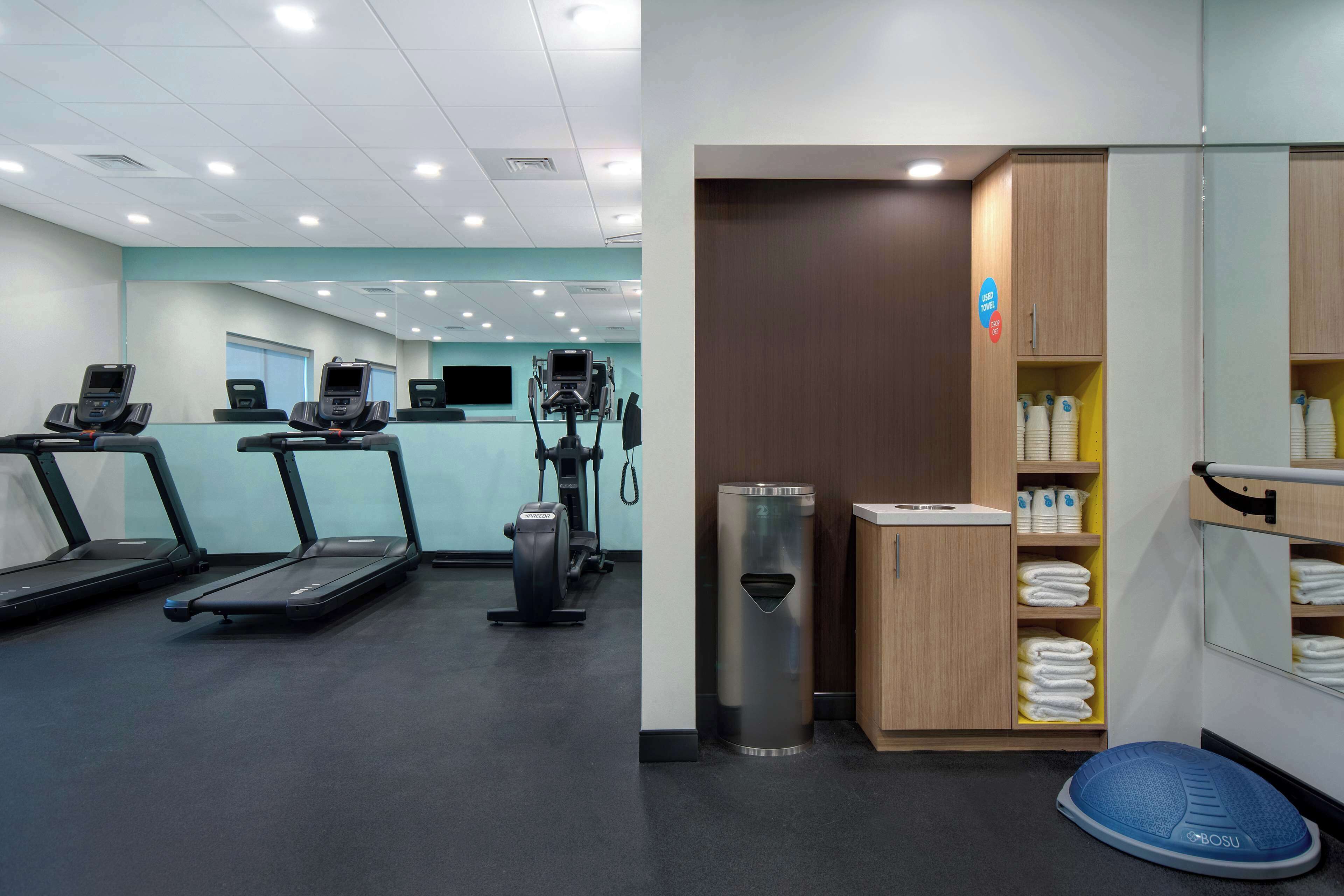 A gym with treadmills, exercise bikes, and a mirrored wall.