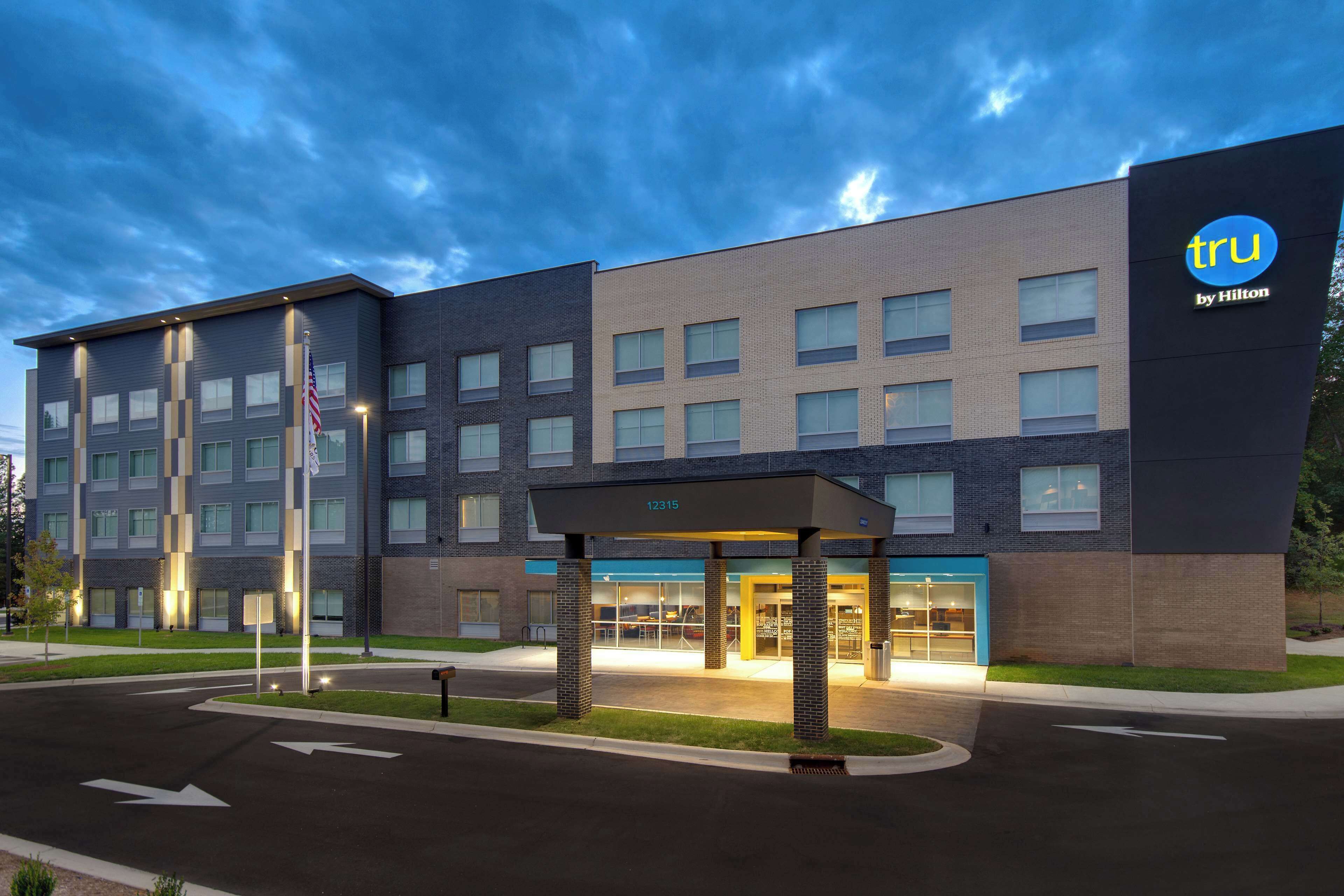 A modern hotel with a flat roof, large windows, and a covered entrance.