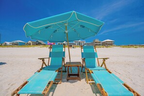 A beach chair and umbrella setup with a view of beachfront properties. - Gulf Shores Surf & Racquet 614A (Gulf Shores)