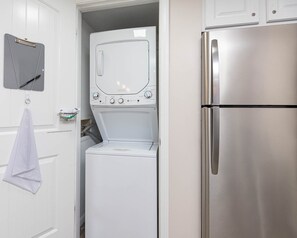 Une cuisine compacte équipée d’un réfrigérateur en acier inoxydable, d’un lave-linge et d’un four à micro-ondes.