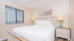 A bedroom with a bed, two bedside tables, a window, and a ceiling fan.