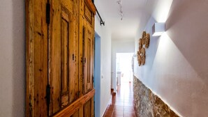 A hallway with wooden doors, a stone wall, and a tiled floor.