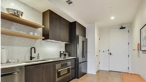 Eine moderne Küche mit dunklen Holzschränken, Edelstahlgeräten und Holzboden.