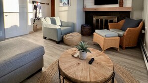 A spacious living room with a large sofa, a round coffee table, and a fireplace.