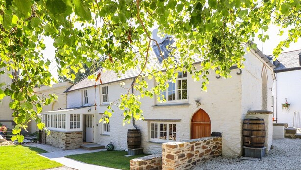 Un bâtiment blanc avec une façade en pierre, une porte en bois et deux tonneaux.