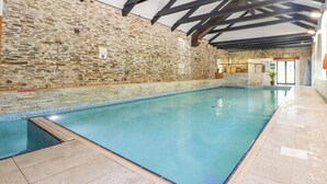 Une piscine intérieure avec des murs en pierre et un sol carrelé.