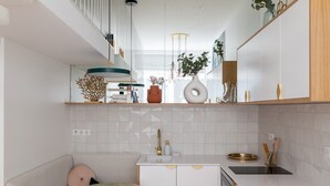 A modern kitchen with white cabinets, a round table, and a built-in oven. - ParisConciergerie - Design studio in Paris (Paris)