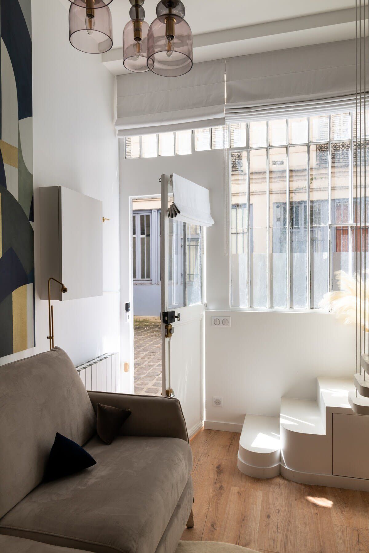 Un salon moderne avec un canapé, une grande fenêtre et une vue sur la rue.