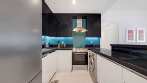 Una cocina moderna con un refrigerador de acero inoxidable, un horno empotrado y una lavadora.
