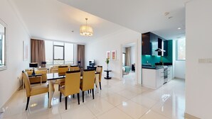 Una habitación de hotel moderna con comedor, cocina y vistas a la ciudad.