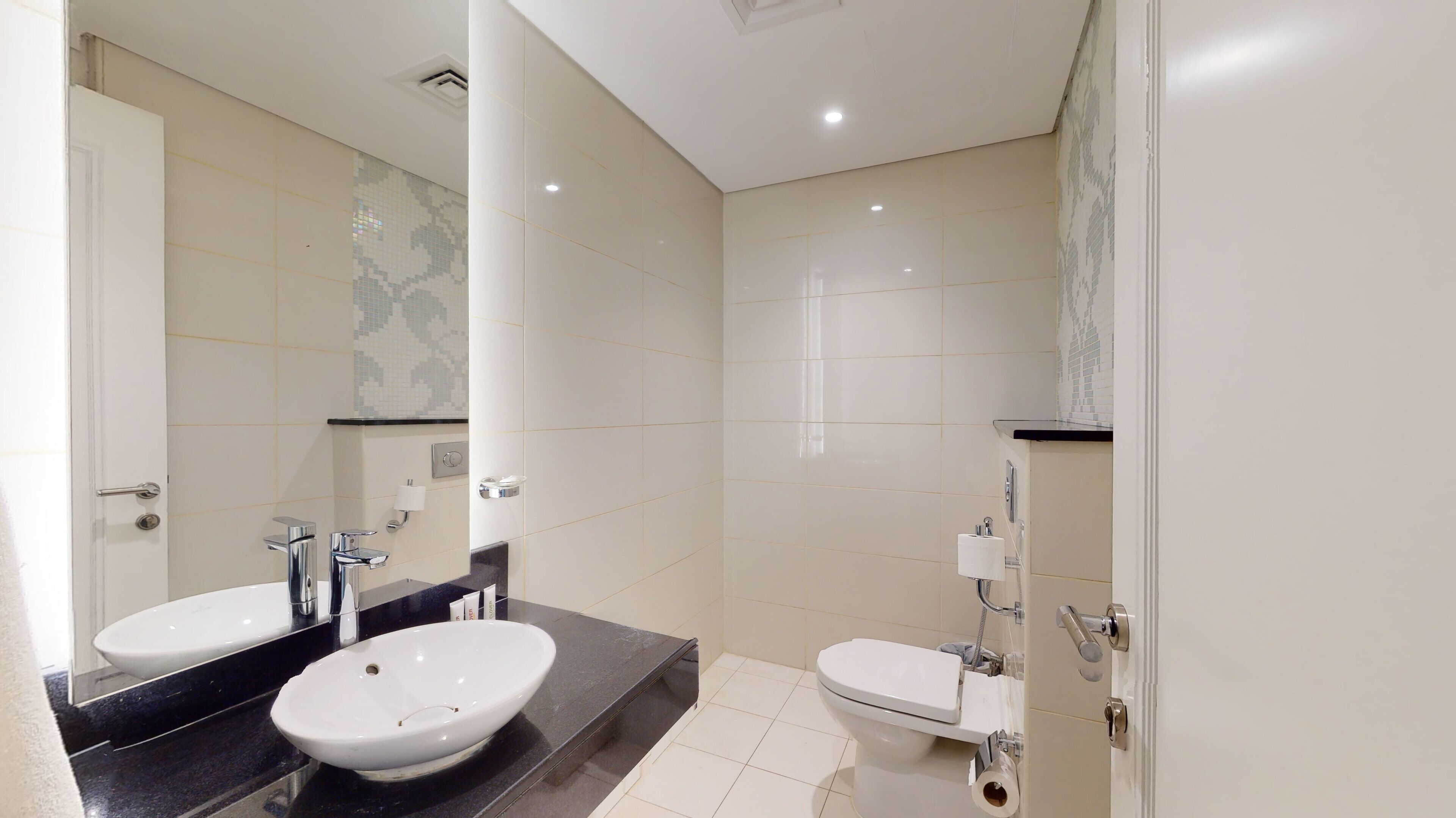 A modern bathroom with two sinks, a toilet, and a shower.
