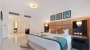 Una habitación de hotel moderna con una cama grande, mesitas de noche, un escritorio y un baño visible al fondo.
