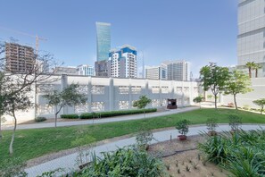 A modern building with a glass facade, surrounded by a well-maintained lawn and potted plants. - GreenFuture - Capital Bay Tower A (Dubai)
