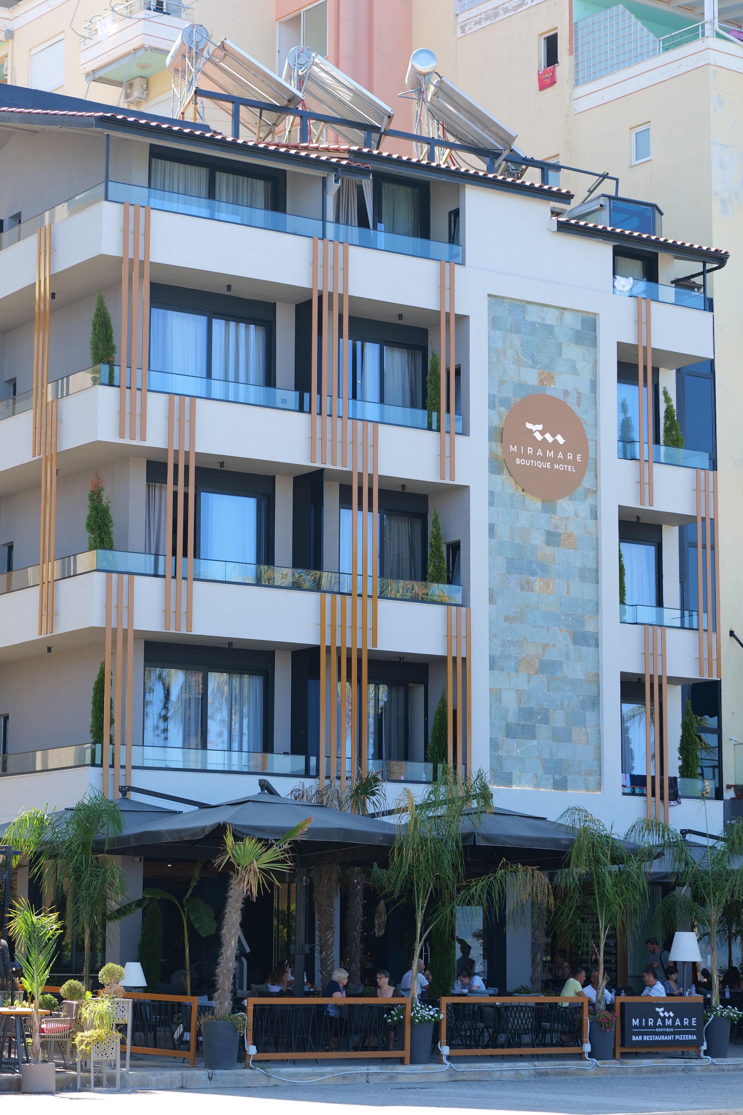 A multi-story hotel with balconies, outdoor seating, and a visible restaurant sign.