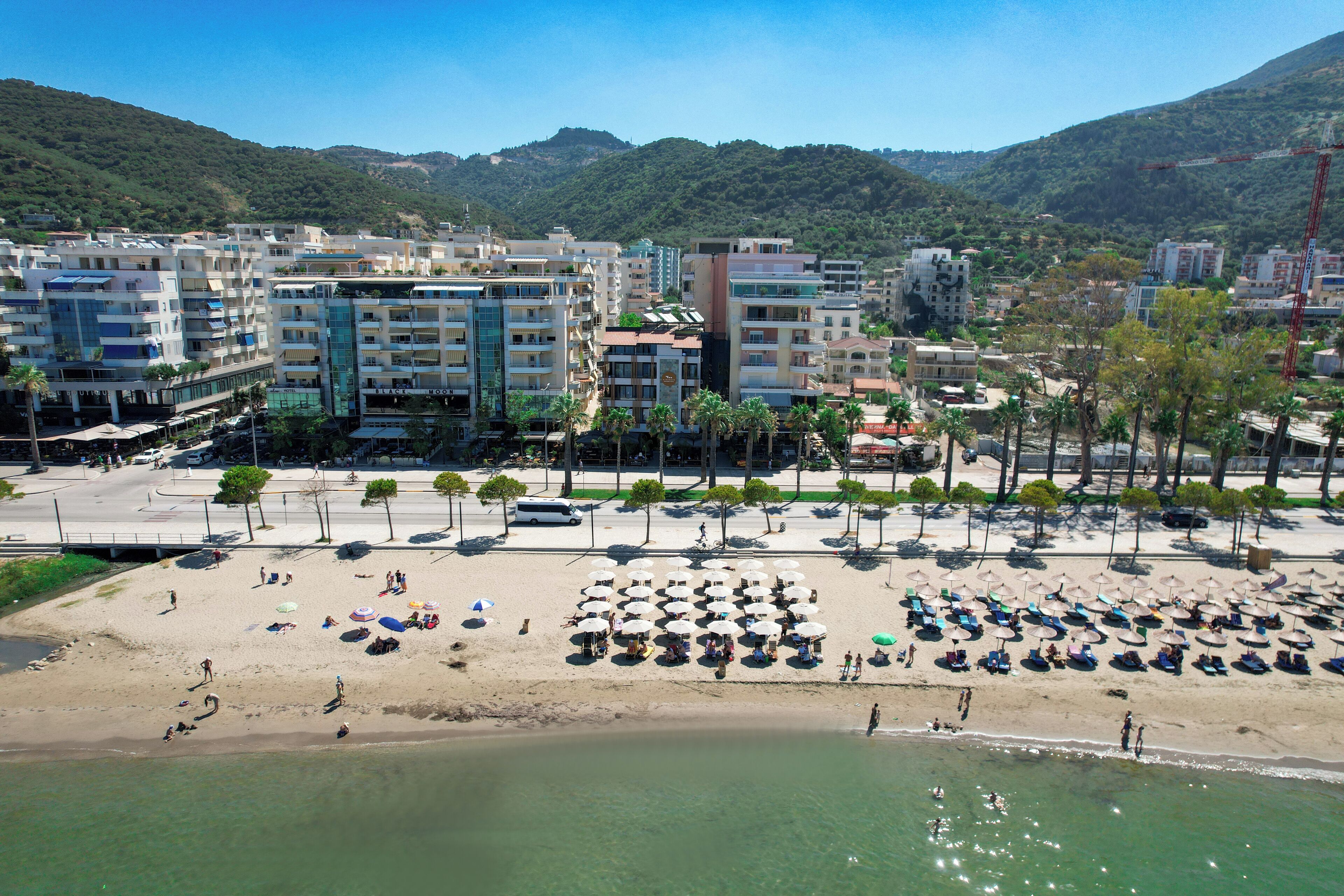 A coastal area with a beach, umbrellas, and buildings.