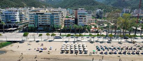 A coastal area with a beach, umbrellas, and buildings.