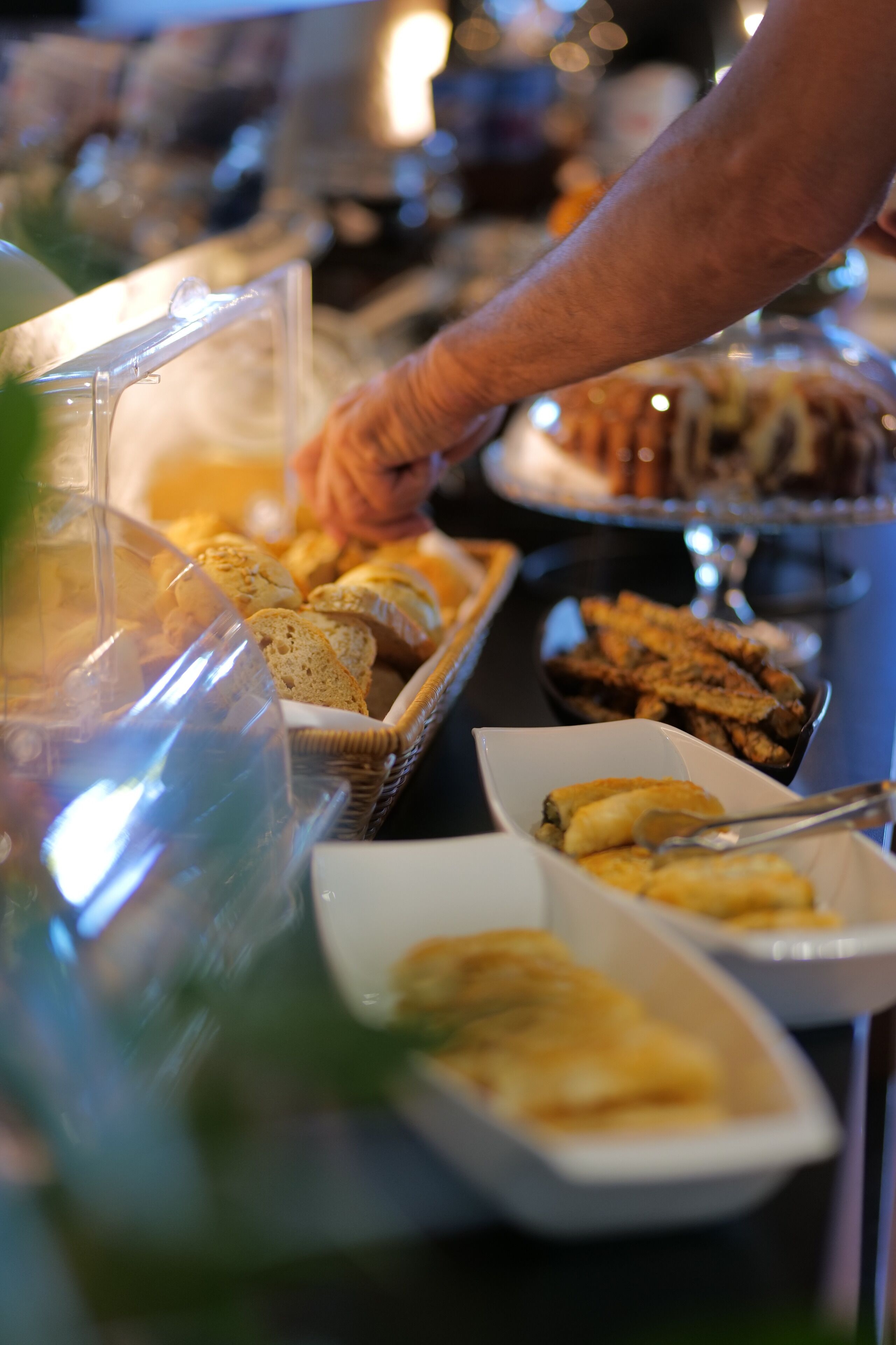 A buffet with various food items including bread, pastries, and a dish in a white bowl.