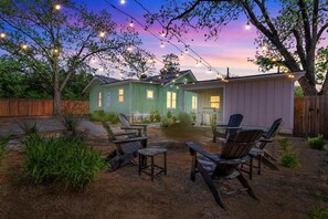 Una casa con patio amoblado, con mobiliario exterior e iluminación de luces colgantes.