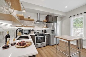 Une cuisine moderne dotée d’un îlot central, d’appareils électroménagers en acier inoxydable et d’étagères en bois.