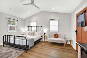 Un dormitorio con cama, sofá, mesita y ventilador de techo.