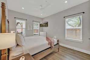Une chambre à coucher avec un lit, des tables de chevet, une lampe et des fenêtres équipées de stores.