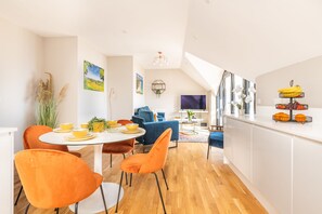Een moderne keuken met een eethoek, met een ronde tafel met stoelen, een blauwe bank en een televisie.