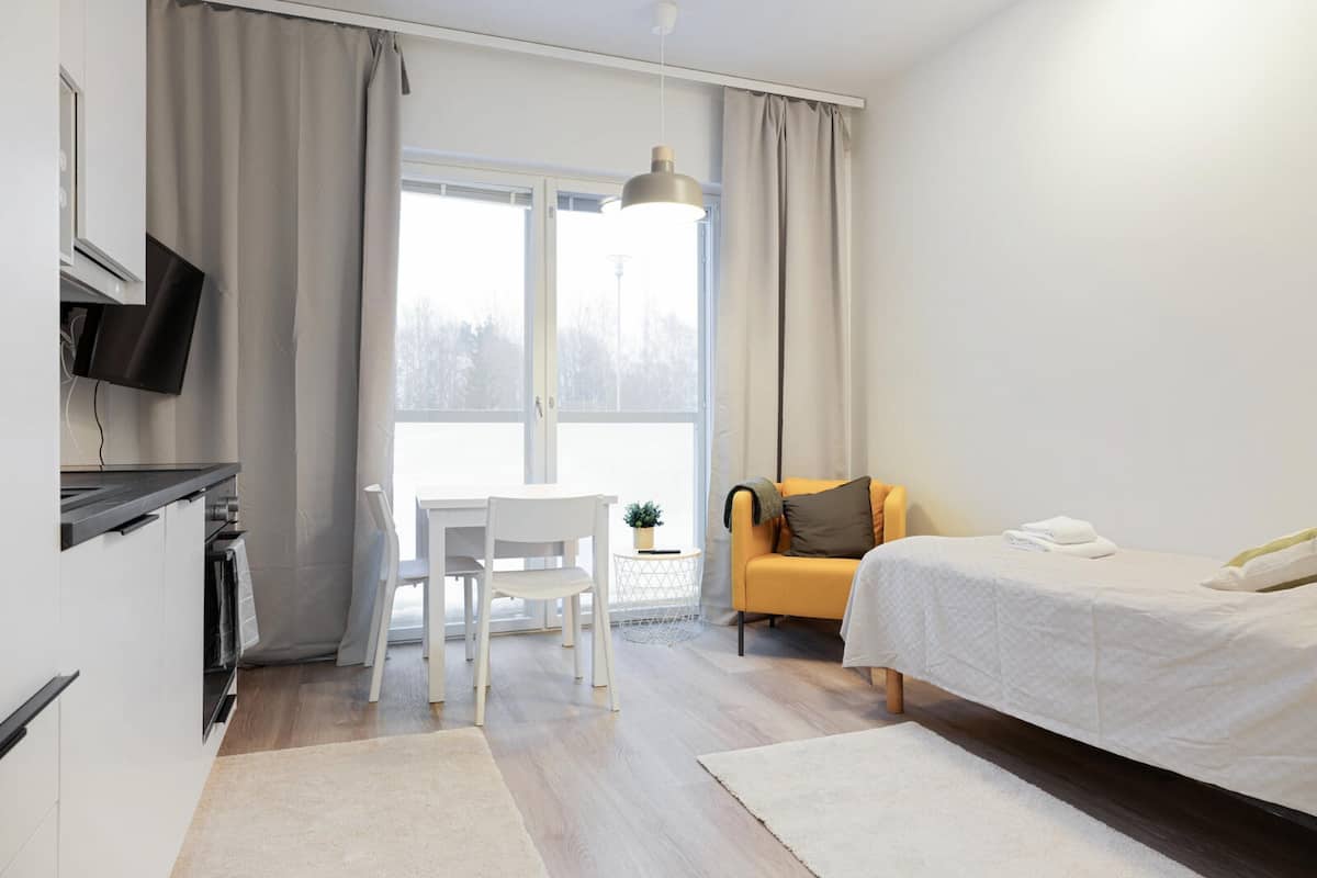 A modern hotel room with a bed, a desk, and a chair.