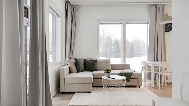 A modern living room with a sofa, coffee table, and dining area. - Forenom Serviced Apts Espoo Saunalahti (Espoo)