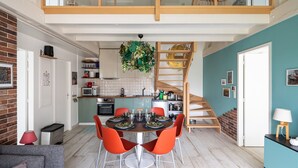 Una cocina moderna con comedor, un dormitorio en entrepiso y una escalera.