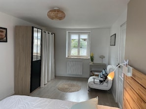 A bedroom with a bed, a chair, a desk, a window, and a radiator. - Ty Karet - Maison pour 6 proche plage (Saint-Cast-le-Guildo)