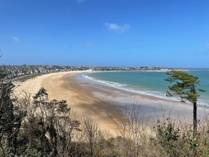Vista costera con playa arenosa, océano y un pueblo distante.