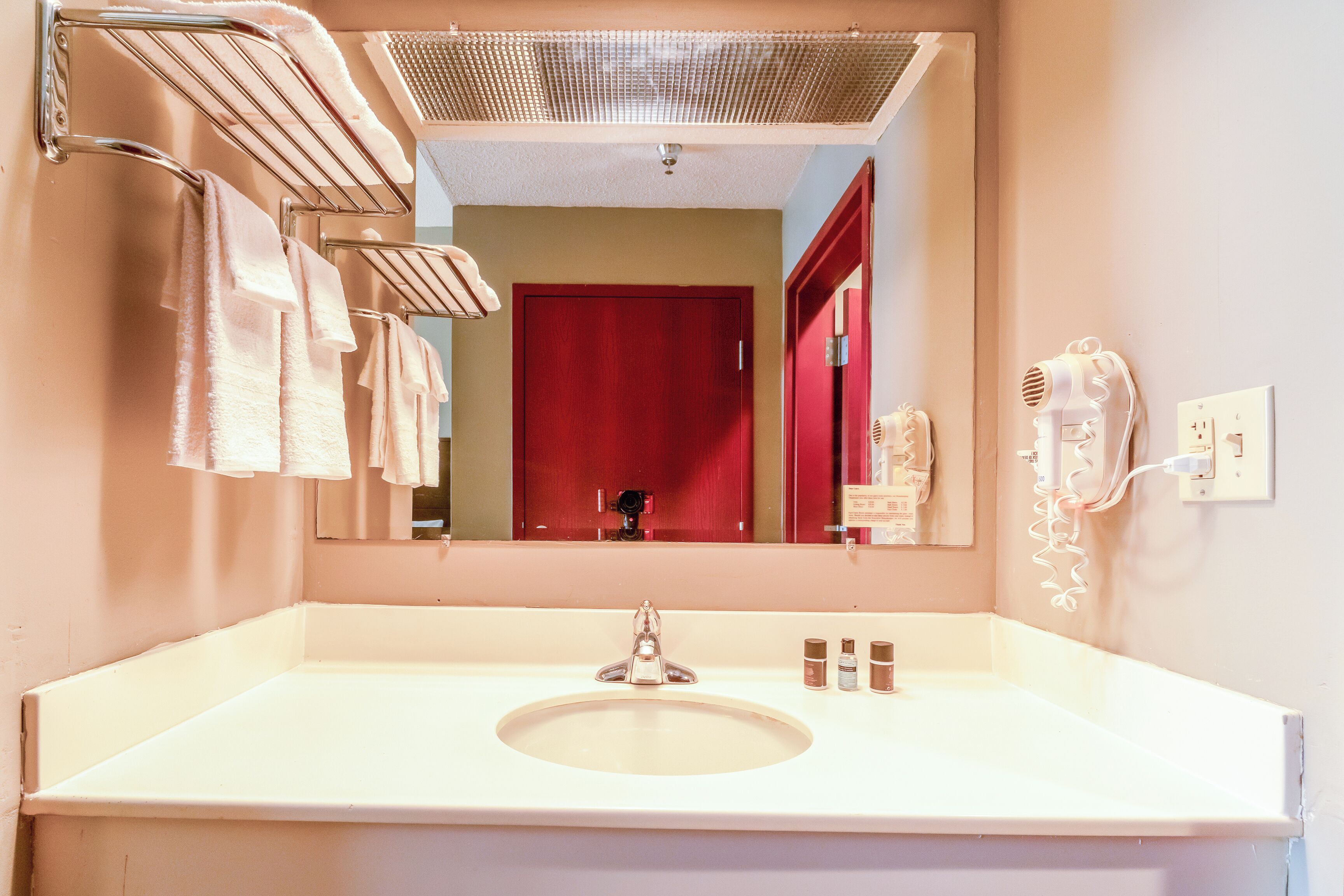 A bathroom with a sink, mirror, towel rack, and hairdryer.