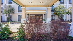 A building entrance with a covered walkway, columns, and potted plants. - Ark Suites By OYO Jonesboro I-555 (Jonesboro)