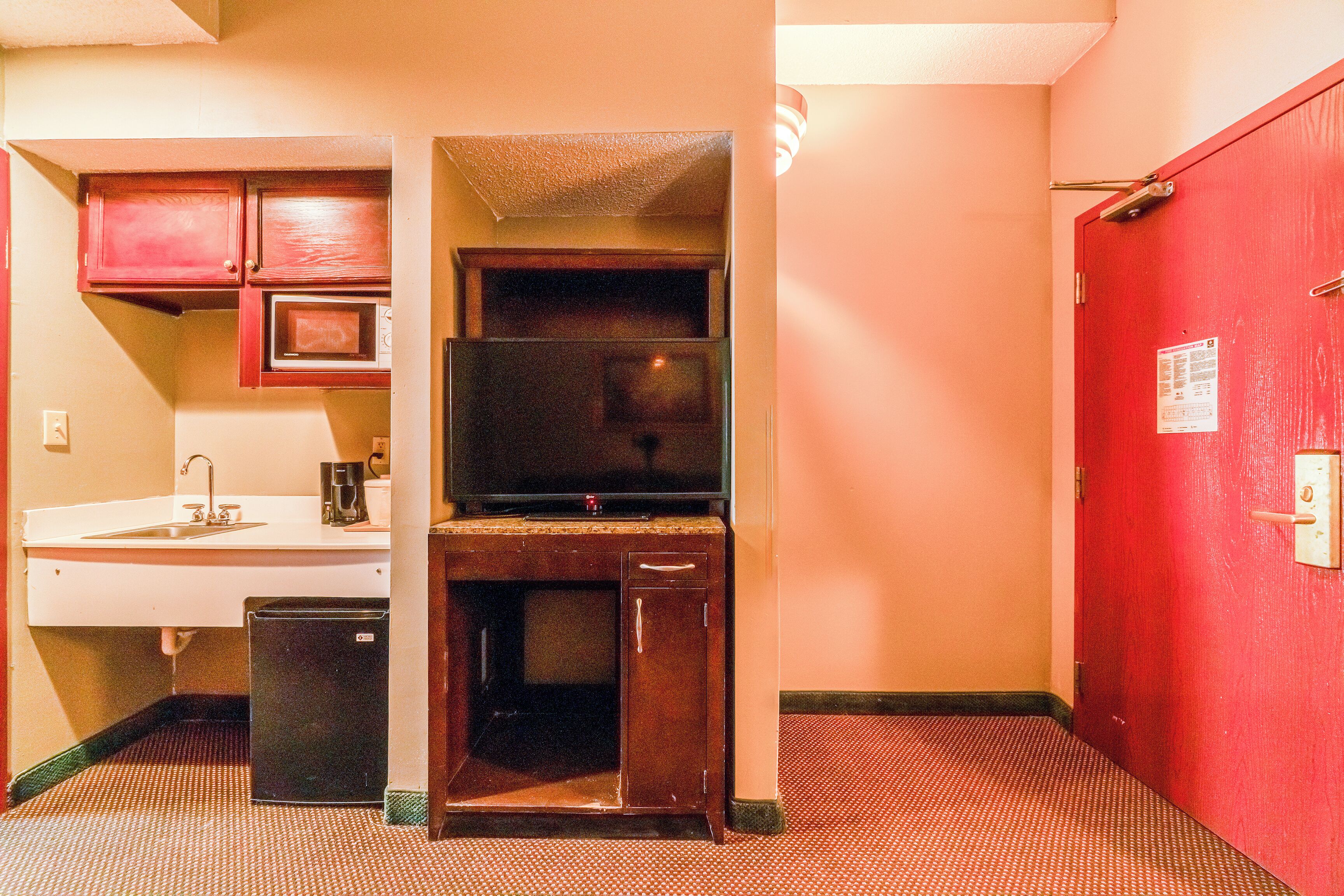 A compact kitchenette with a microwave, sink, and small refrigerator.