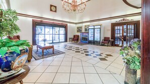 A spacious lobby with a chandelier, checkered floor tiles, a large vase with plants, and a clock on the wall. - Ark Suites By OYO Jonesboro I-555 (Jonesboro)
