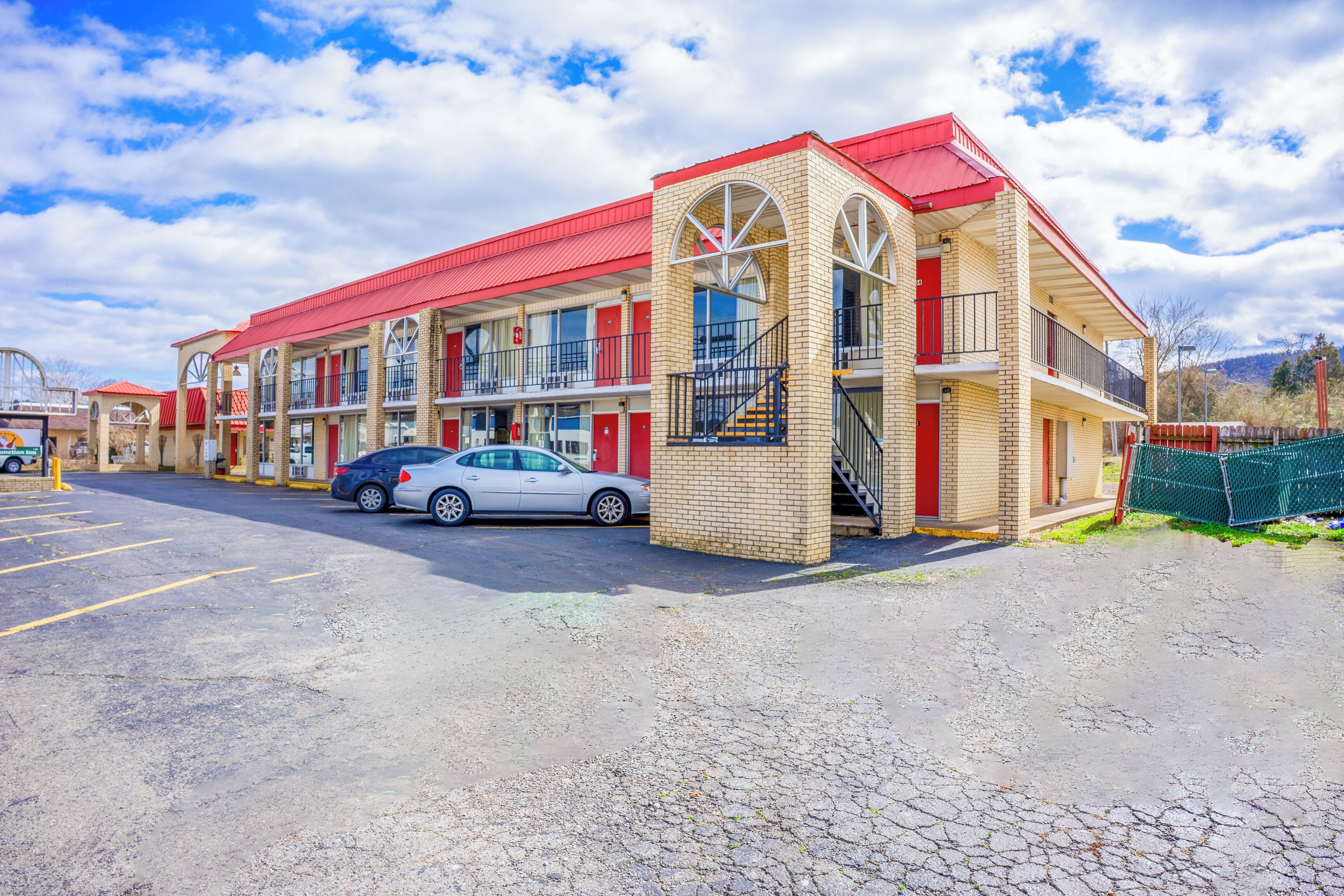 A motel with multiple floors, red awnings, and a parking lot.