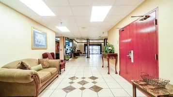 Un vestíbulo de hotel con un sofá color crema, una puerta roja y un piso de baldosas.