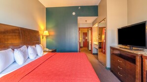 A hotel room with a large bed, a television, and a bathroom visible through an open door. - Ark Suites By OYO Jonesboro I-555 (Jonesboro)