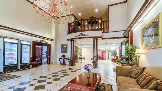 A spacious lobby with a checkered floor, a wooden coffee table, a sofa, and a chandelier. - Ark Suites By OYO Jonesboro I-555 (Jonesboro)