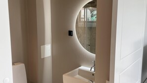 Un baño moderno con inodoro, lavamanos y espejo.