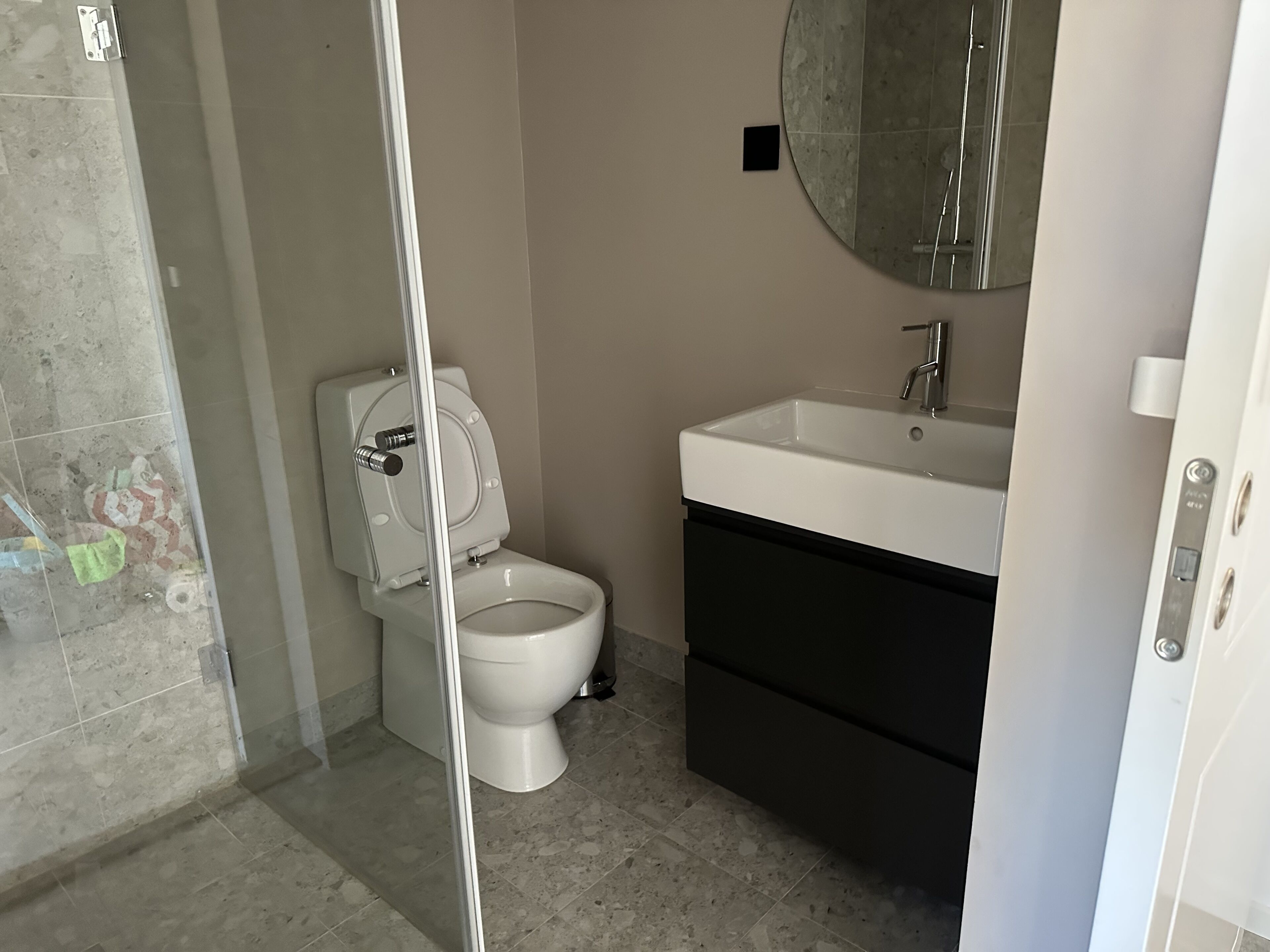 A bathroom with a toilet, sink, and mirror.