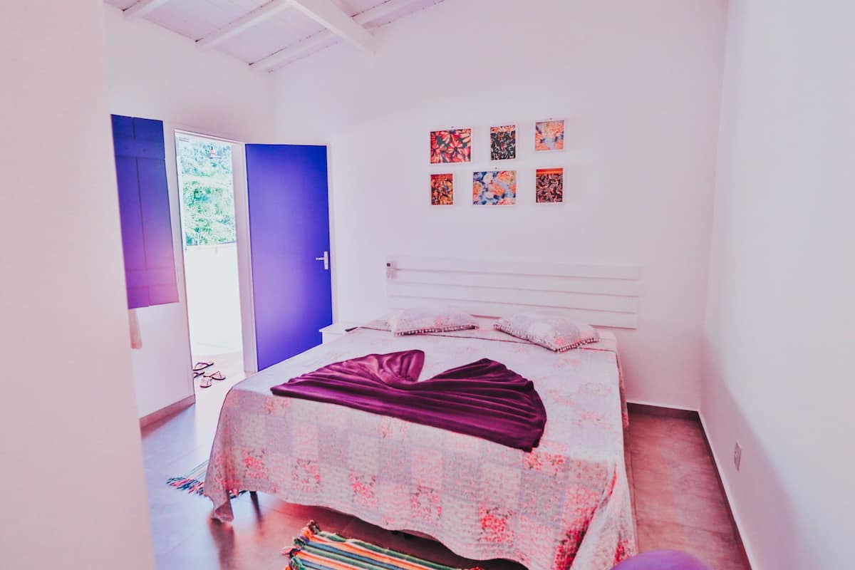 A bedroom with a bed, a door, and a wall with framed pictures.