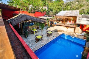 Zona de piscina con suelo de piedra, piscina y mobiliario exterior.