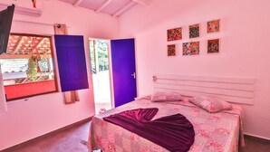 A bedroom with a bed, a window with curtains, a door, and wall art. - La Gloria House (Ilhabela)